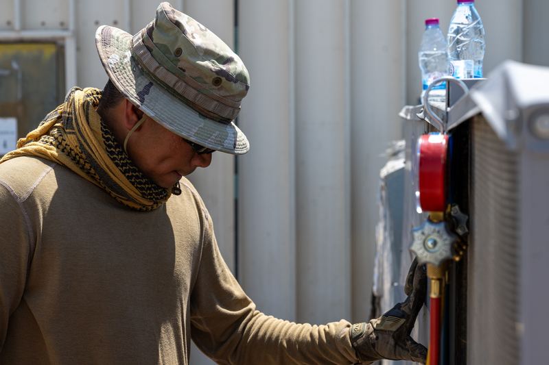 A heating, ventilation and air conditioning technician assigned to the 379th Expeditionary Civil Engineer Squadron inspects a repaired A/C unit for structural integrity at an undis